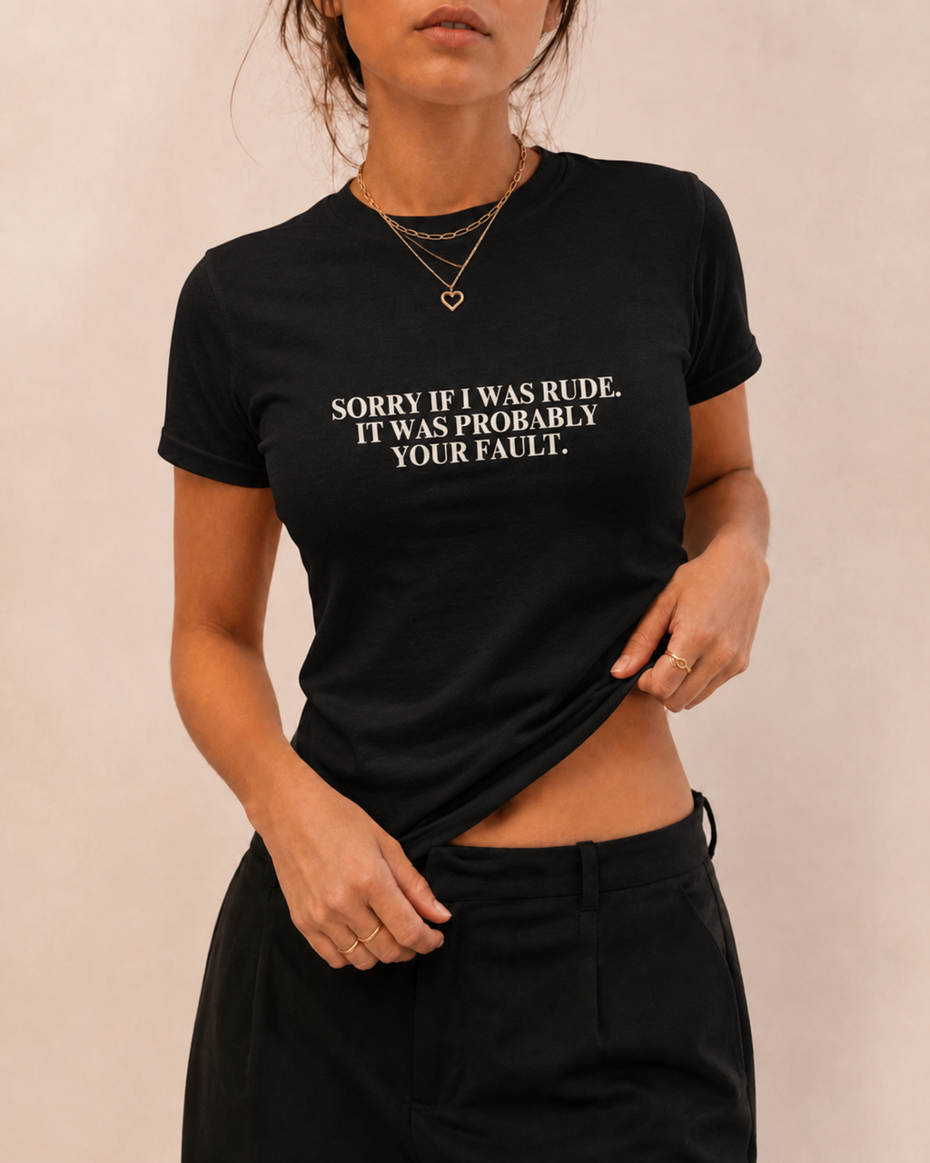 Woman wearing a fitted black “Sorry If I Was Rude, It Was Probably Your Fault” graphic T-shirt with black trousers