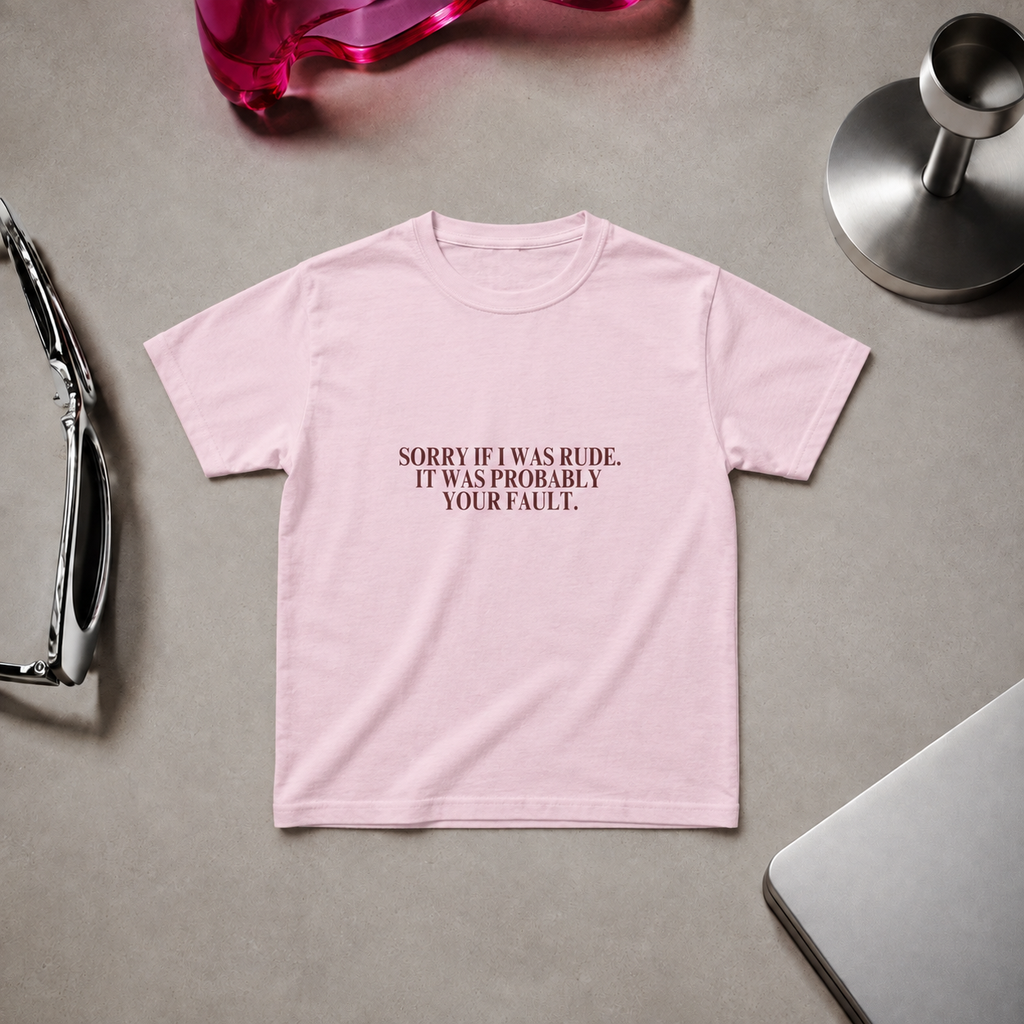 Woman wearing a fitted light pink “Sorry If I Was Rude, It Was Probably Your Fault” graphic T-shirt with black trousers