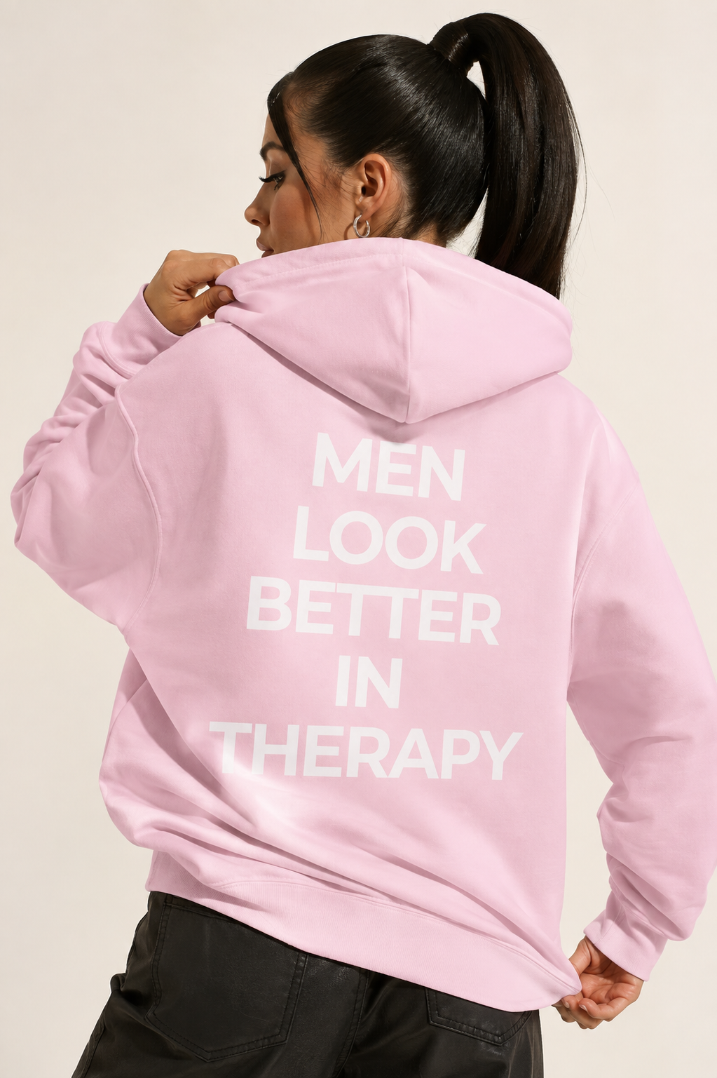 Bright pink unisex hoodie with a white “Men Look Better in Therapy” statement print across the back.
