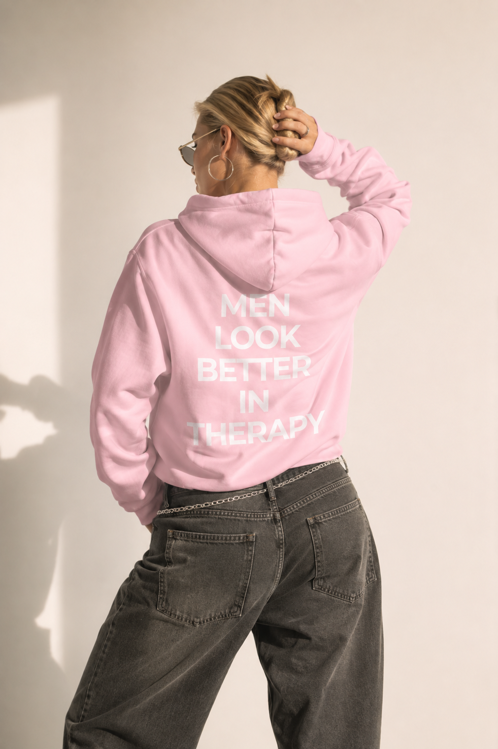 Light pink unisex hoodie with a white “Men Look Better in Therapy” statement print across the back.
