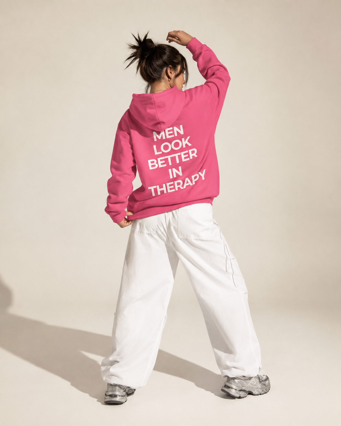 Bright pink unisex hoodie with a white “Men Look Better in Therapy” statement print across the back.
