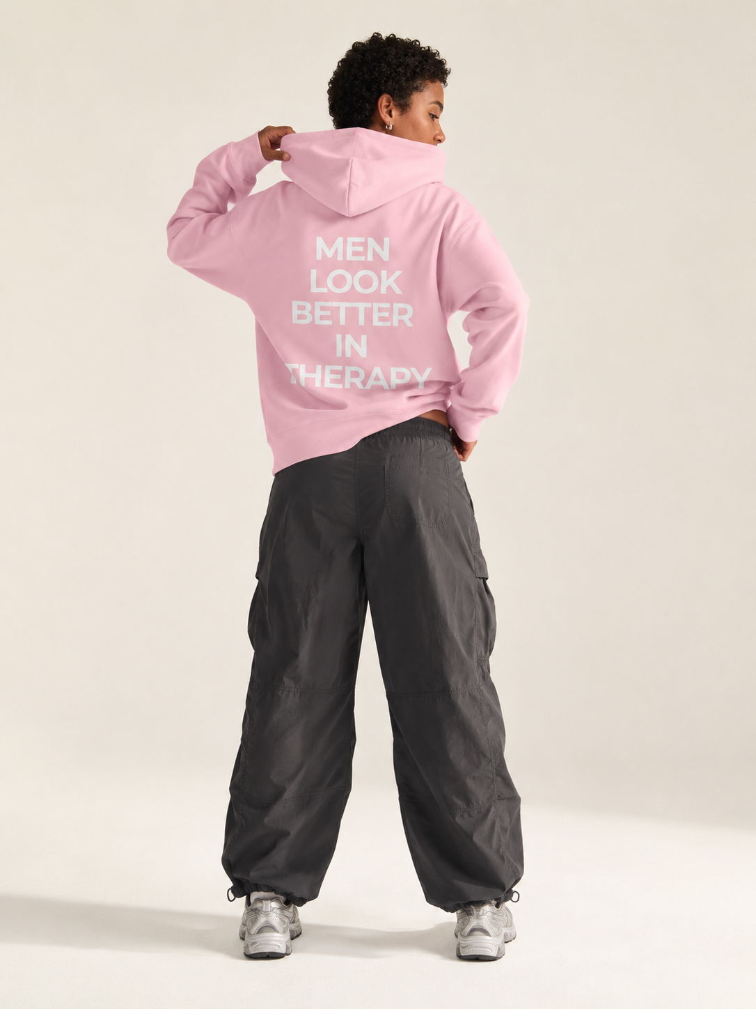 Light pink unisex hoodie with a white “Men Look Better in Therapy” statement print across the back.
