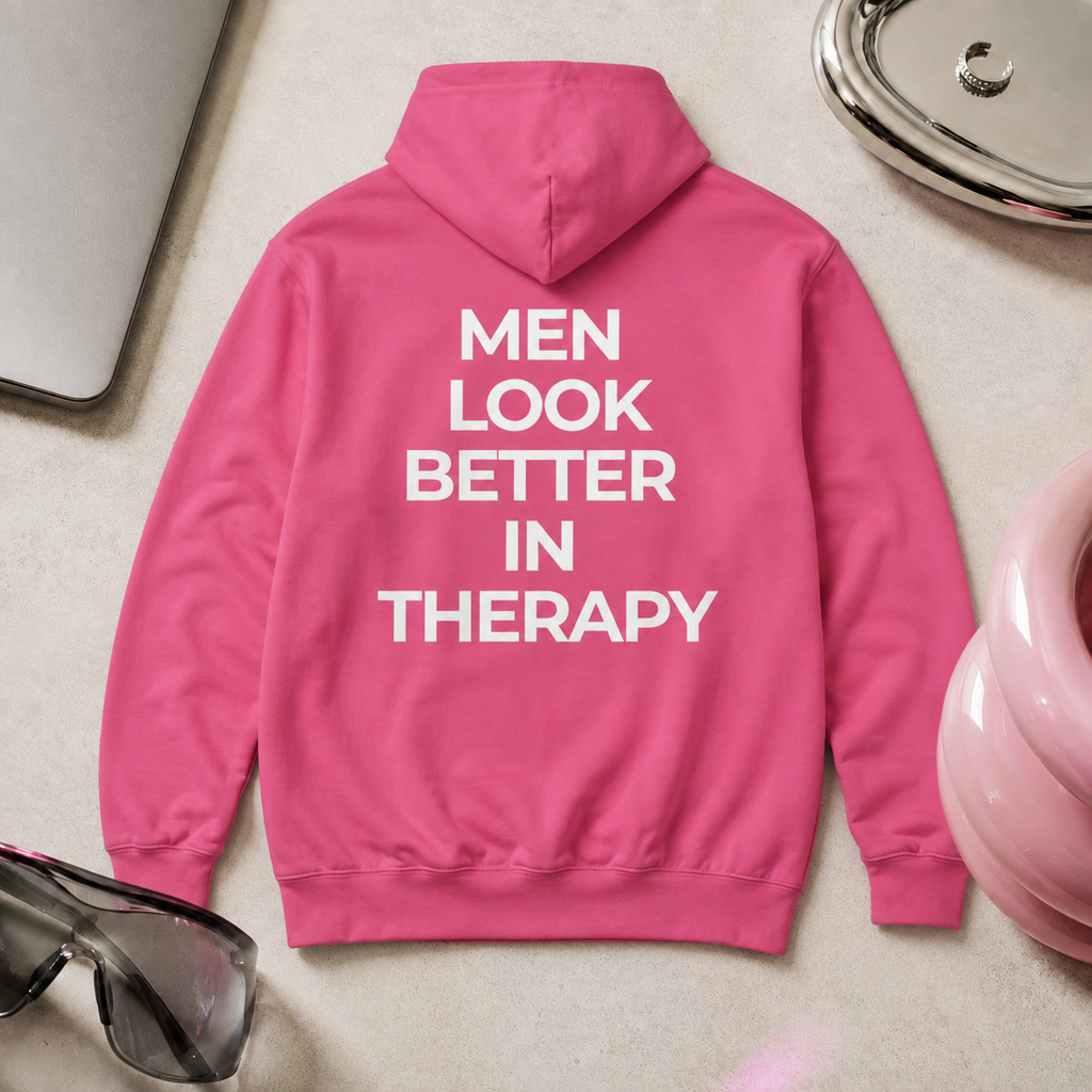 Bright pink unisex hoodie with a white “Men Look Better in Therapy” statement print across the back.
