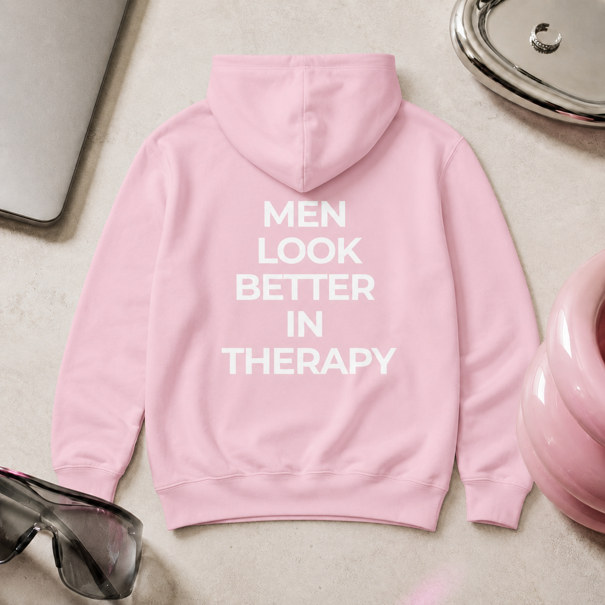 Light pink unisex hoodie with a white “Men Look Better in Therapy” statement print across the back.
