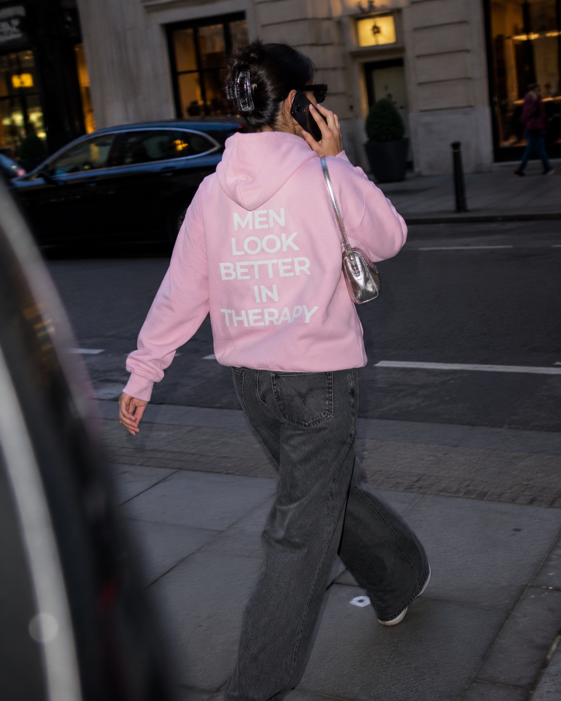 Light pink unisex hoodie with a white “Men Look Better in Therapy” statement print across the back.

