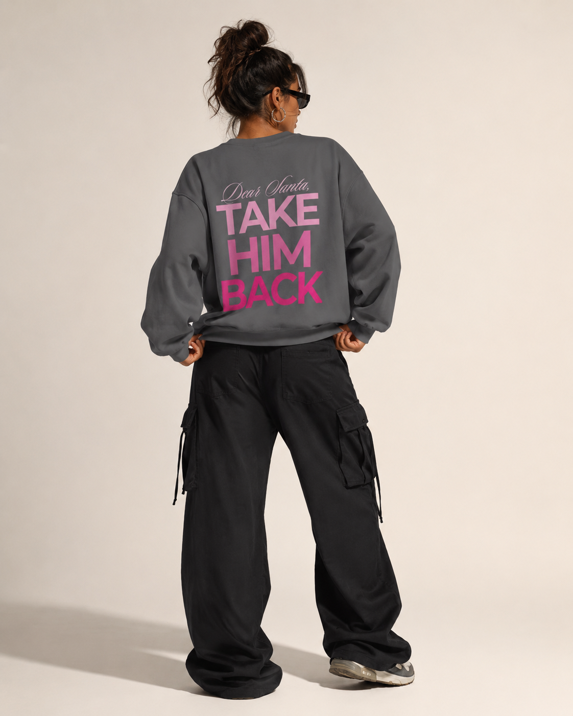 Model wearing a charcoal Dear Santa Take Him Back graphic sweatshirt with black trousers