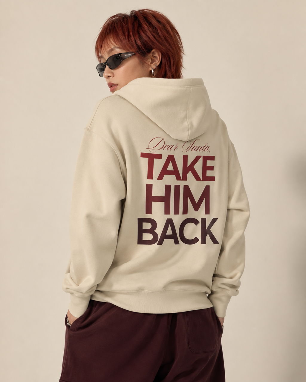 Back view of a cream Dear Santa Take Him Back graphic hoodie with dark red lettering