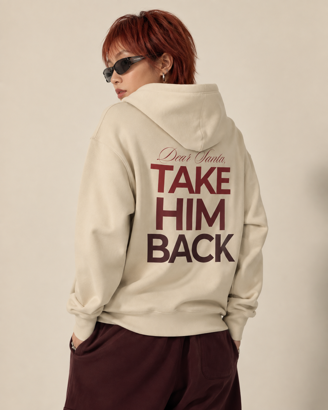 Back view of a cream Dear Santa Take Him Back graphic hoodie with dark red lettering