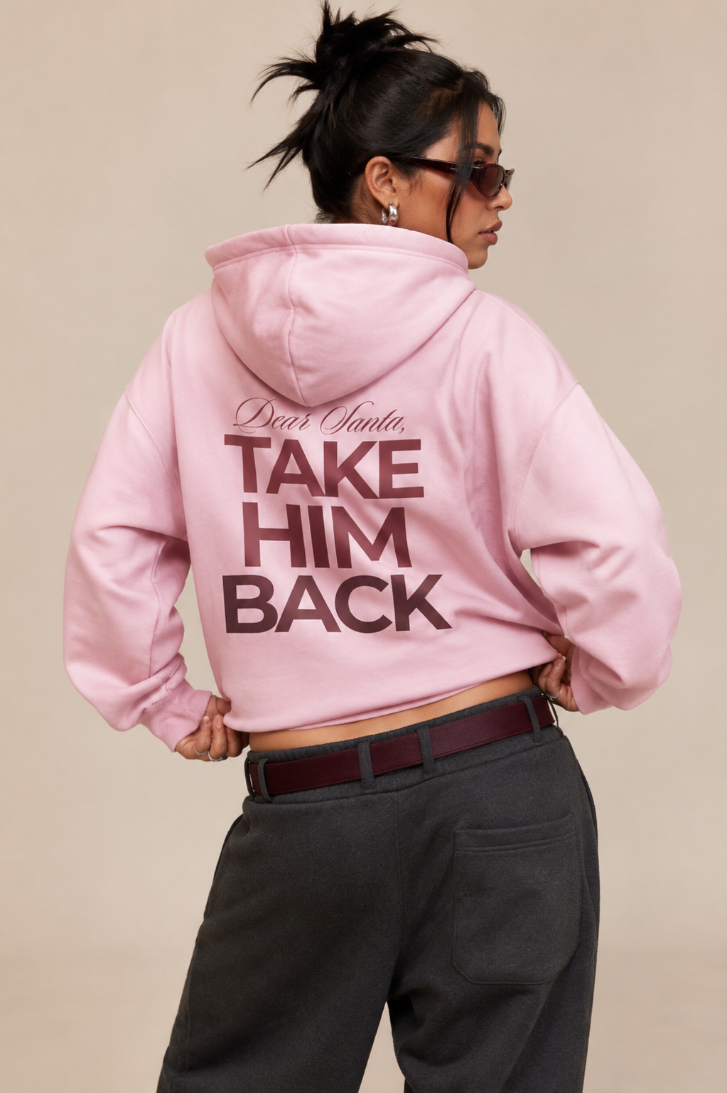 Model wearing a light pink Dear Santa Take Him Back hoodie with black trousers