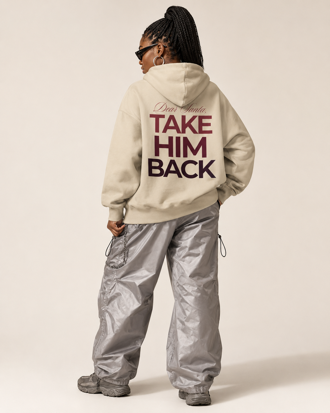Back view of a cream Dear Santa Take Him Back hoodie styled with silver trousers